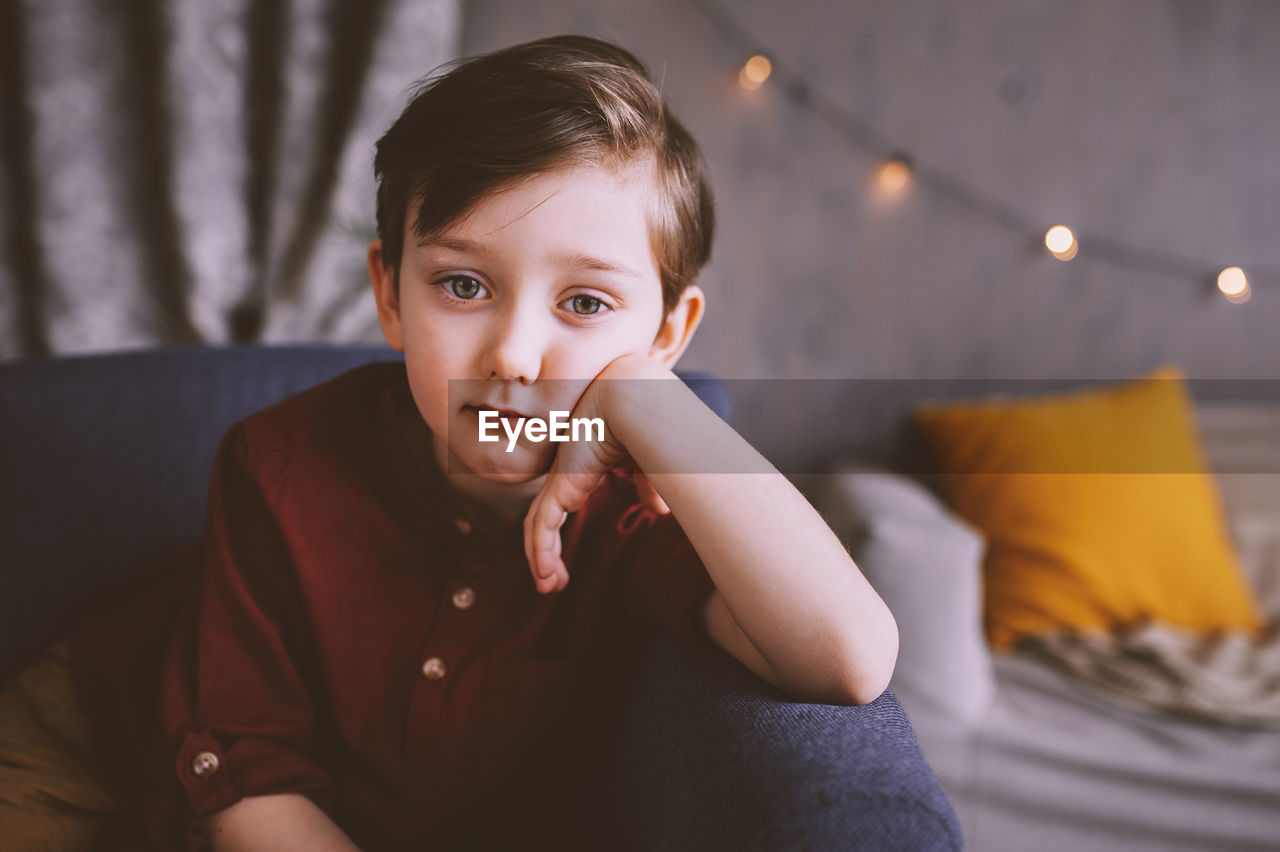 Portrait of cute boy sitting on chair at home