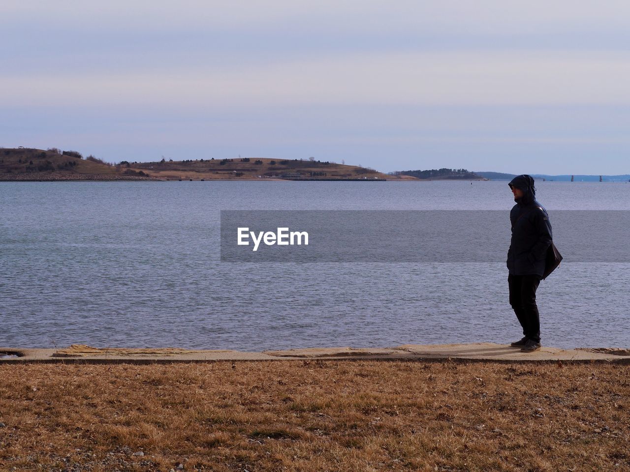 Full length of man standing at lakeshore against sky