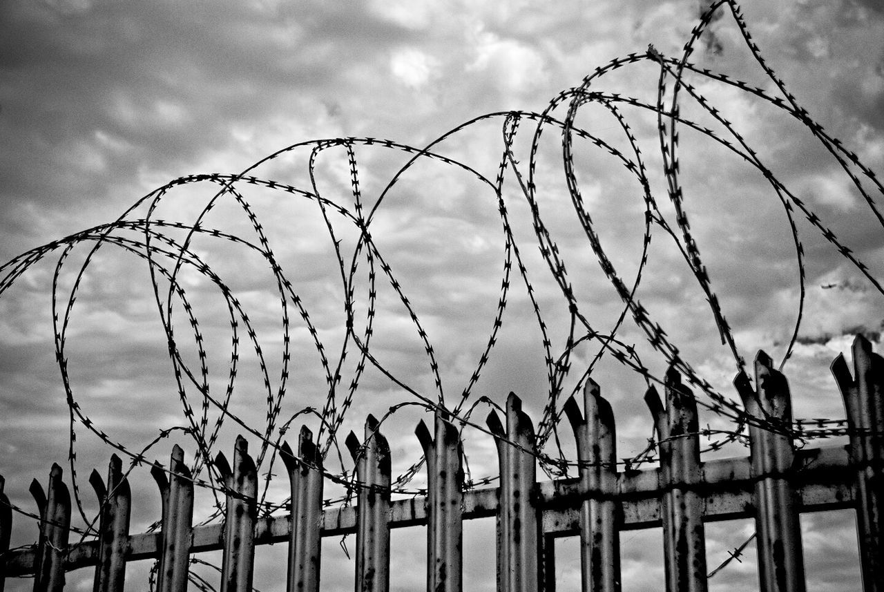 Low angle view of barbed wire against cloudy sky