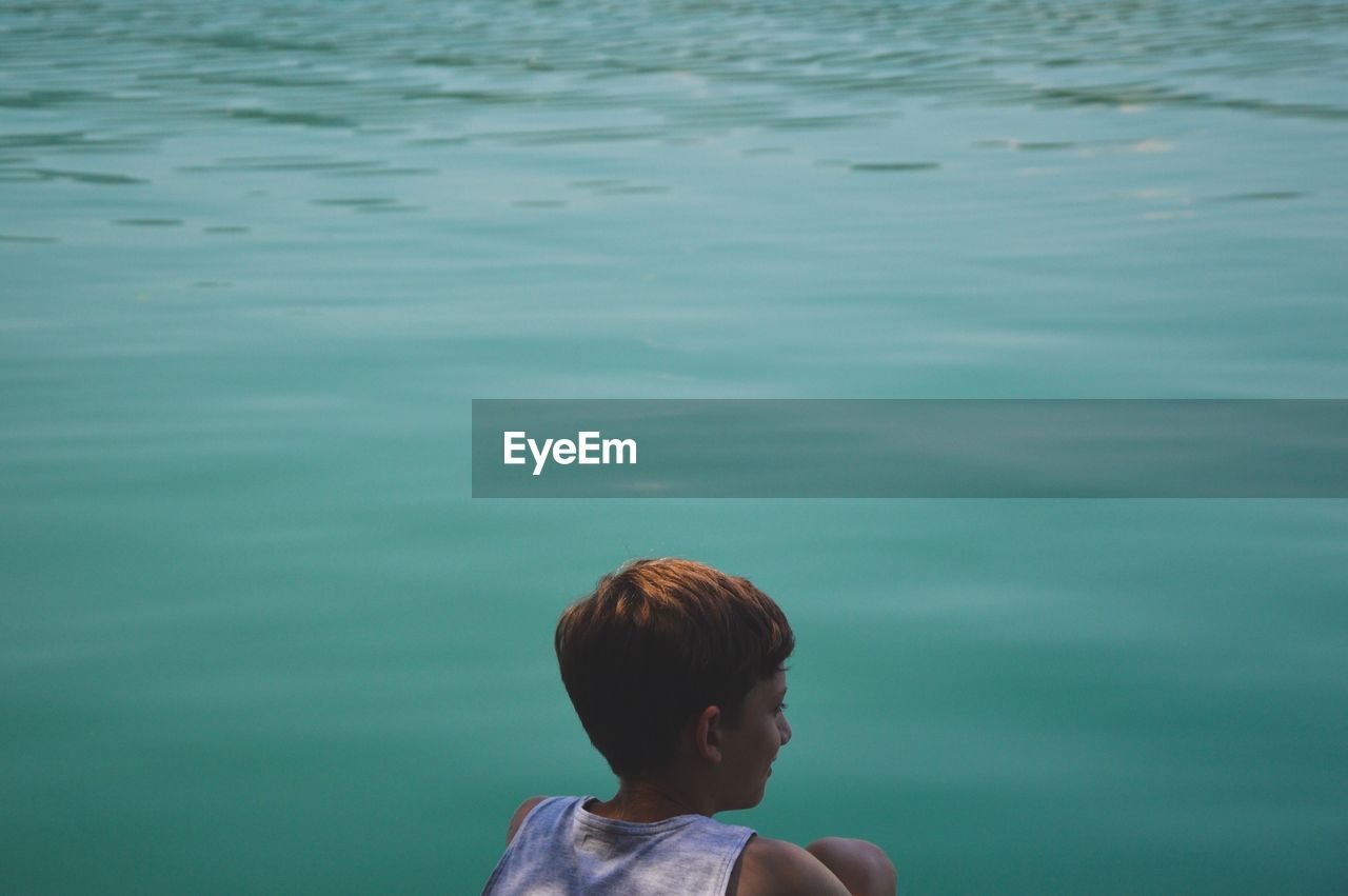 Rear view of boy against turquoise lake