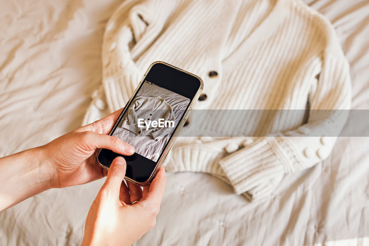 Close-up of woman's hands taking picture of her clothes. selling used clothes online, reuse 