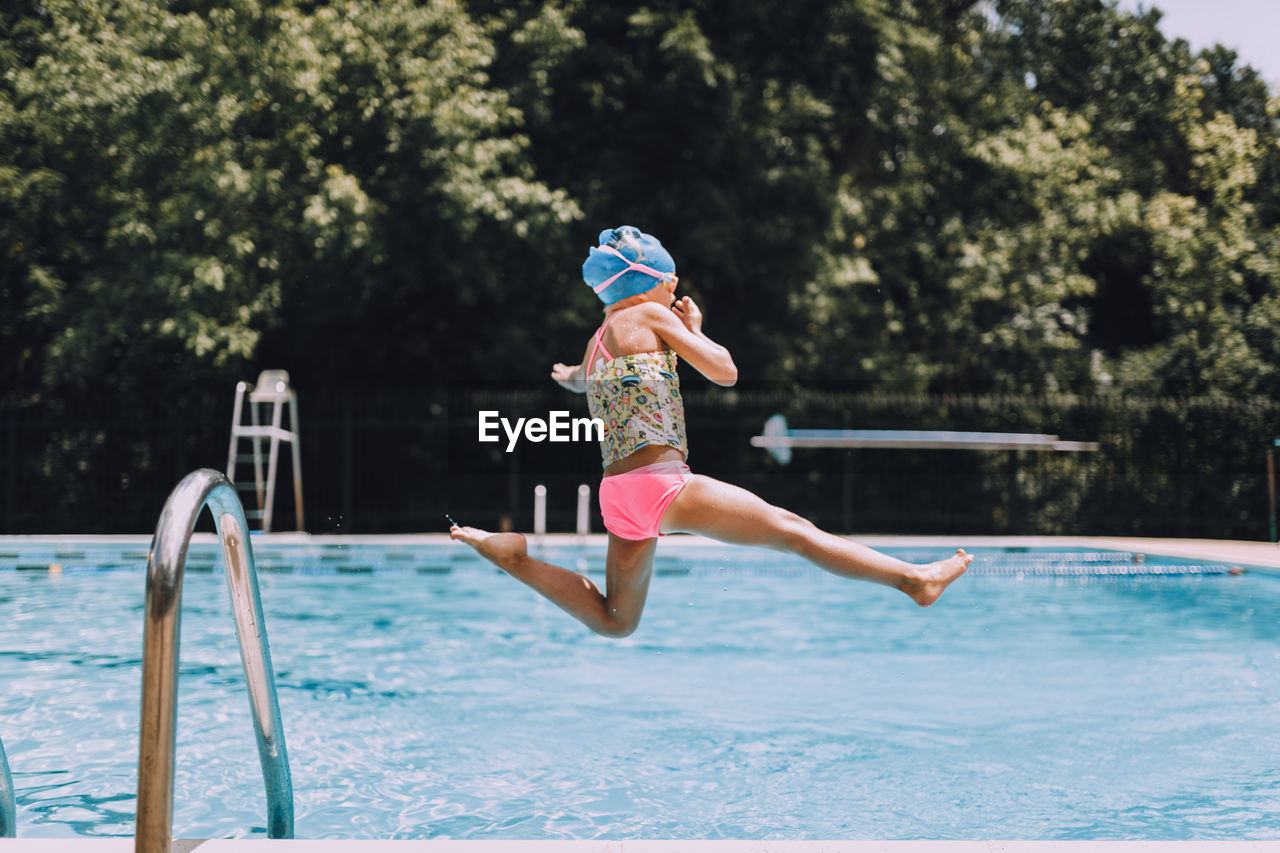 Side view of girl diving into swimming pool