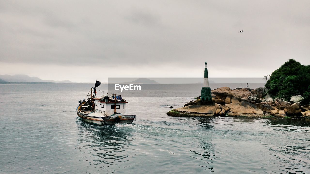 High angle view of boat in sea by rock formations against sky