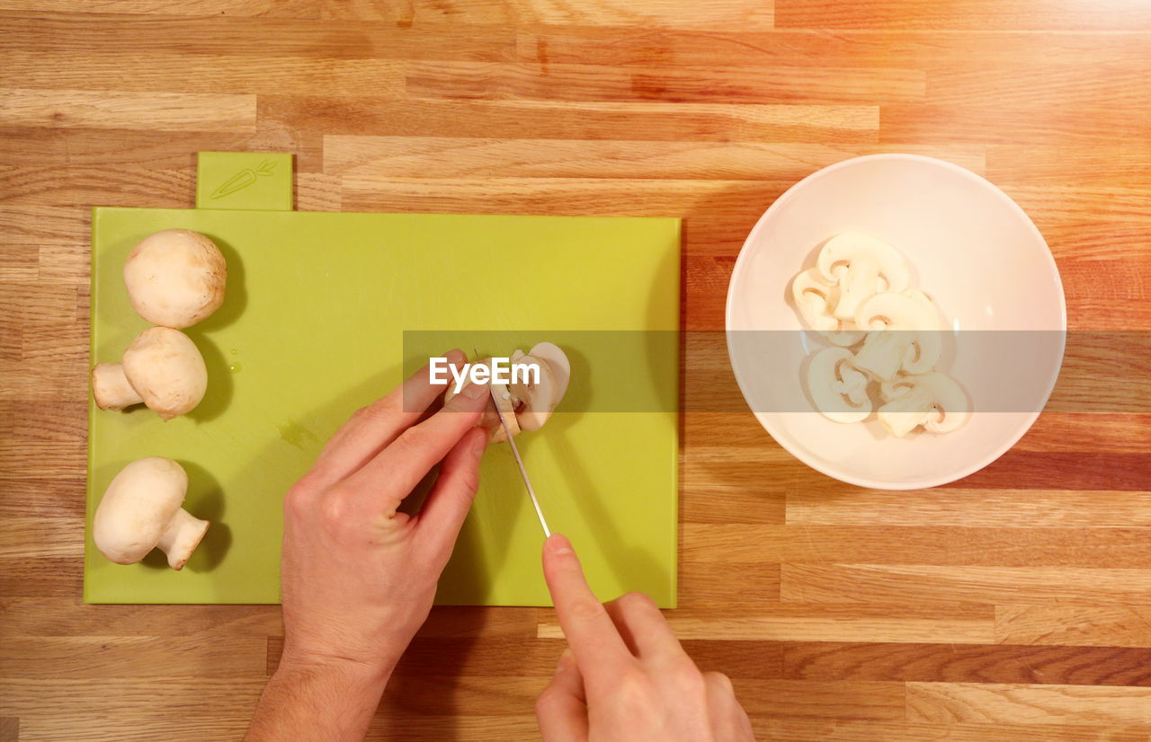 Directly above shot of woman cutting mushrooms at table