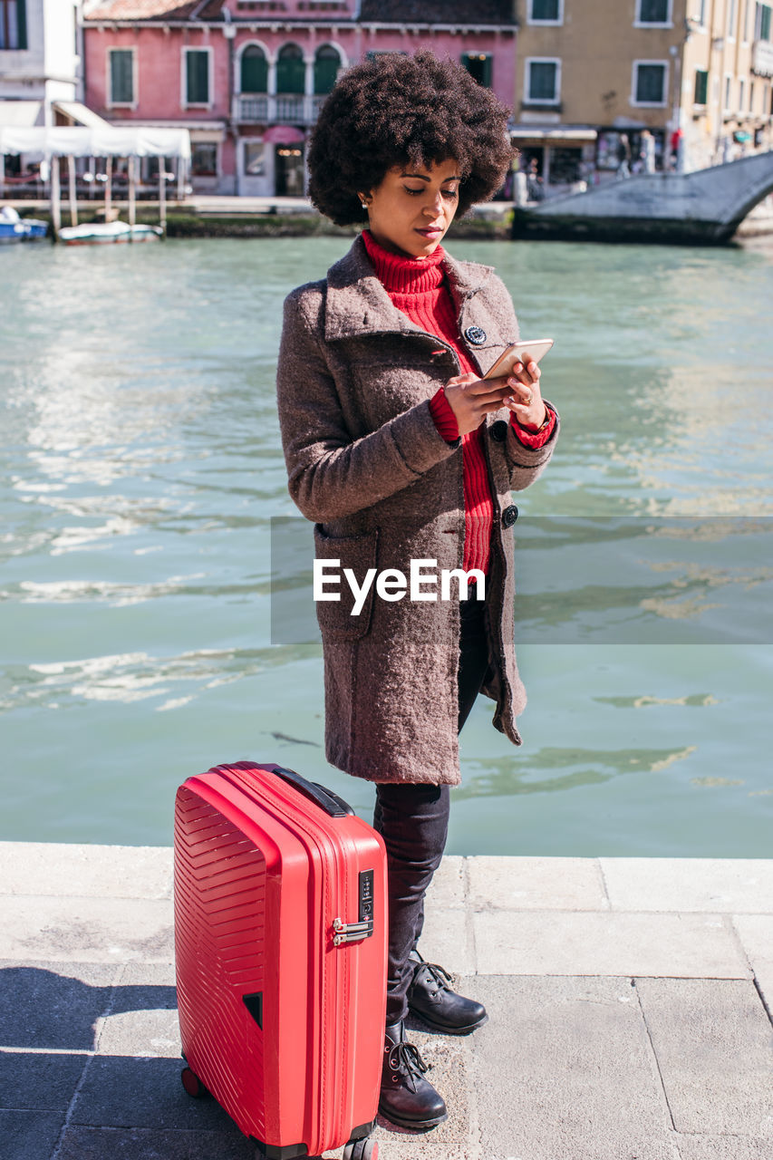 Young tourist woman checking smart mobile phone