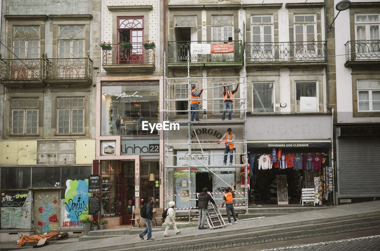 PEOPLE WALKING ON ROAD AGAINST BUILDINGS