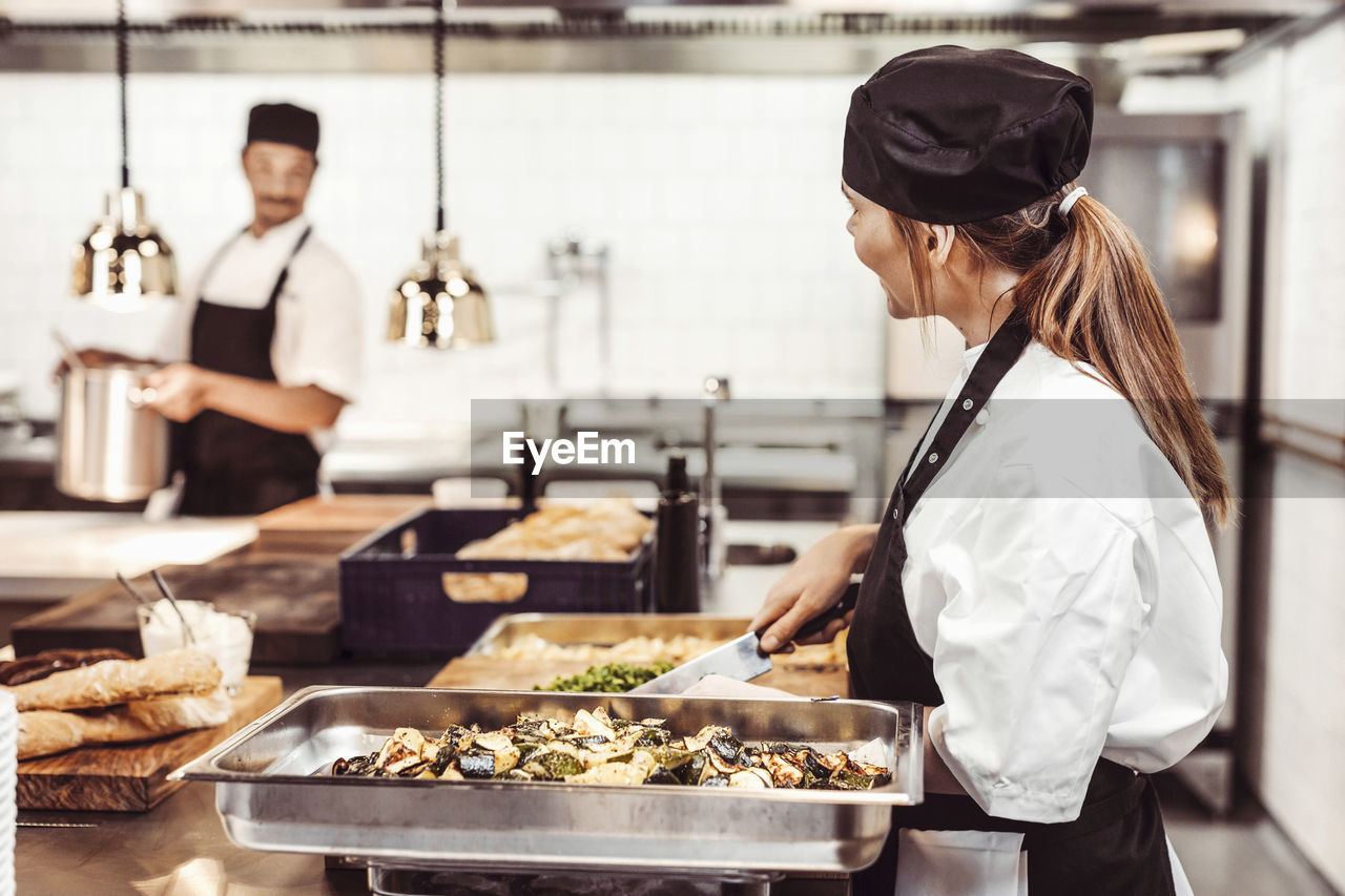 Female chef chopping vegetables in commercial kitchen