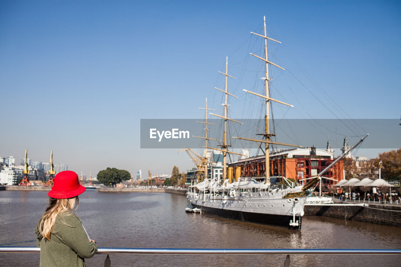 Woman standing on harbor against clear sky