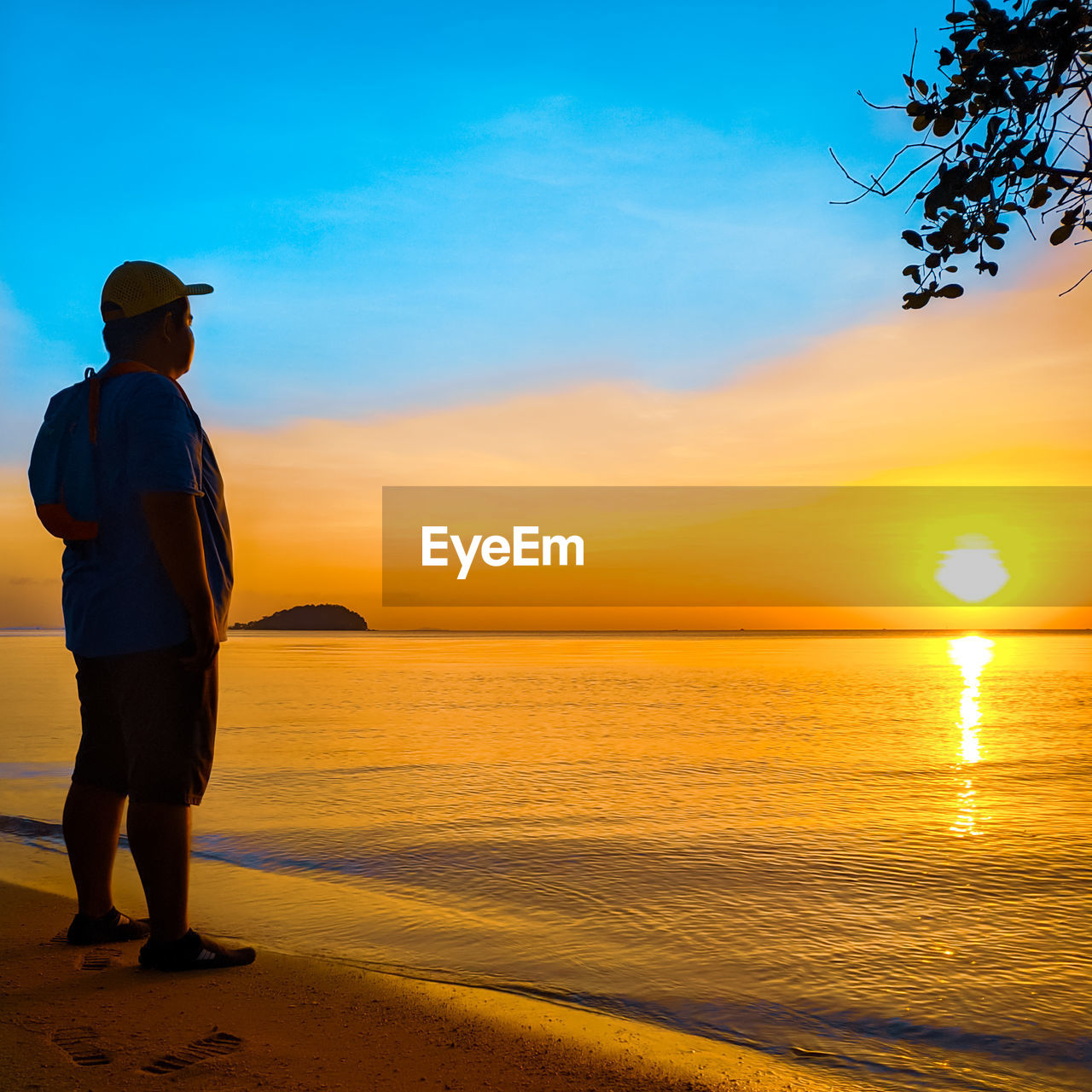 REAR VIEW OF MAN STANDING ON BEACH