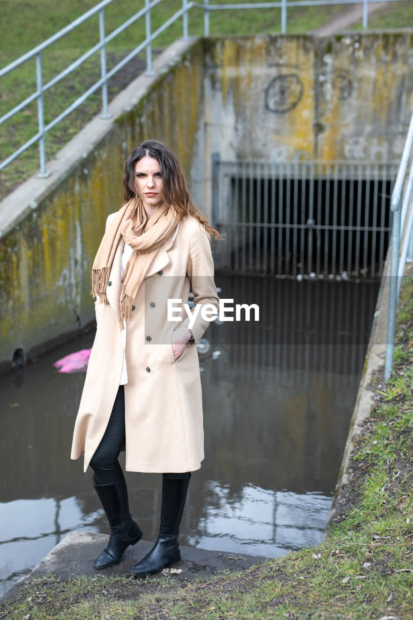 PORTRAIT OF BEAUTIFUL YOUNG WOMAN STANDING AGAINST WATER