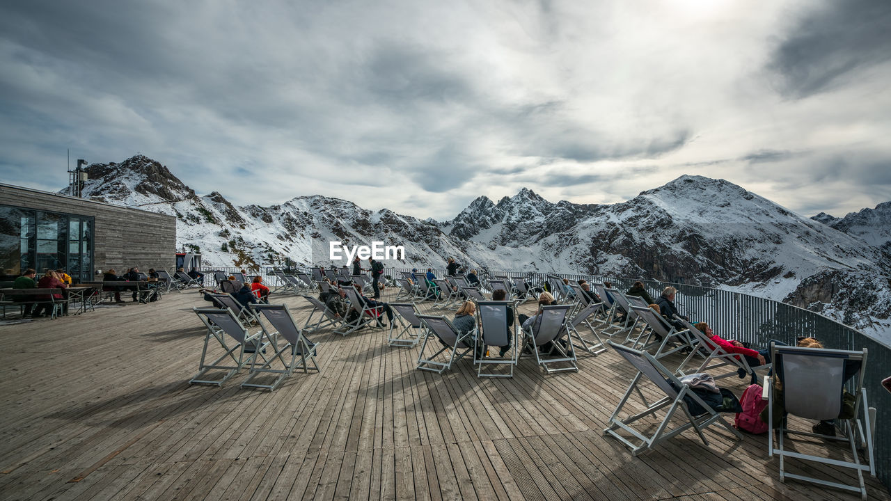 PEOPLE WALKING ON SNOWCAPPED MOUNTAIN AGAINST SKY