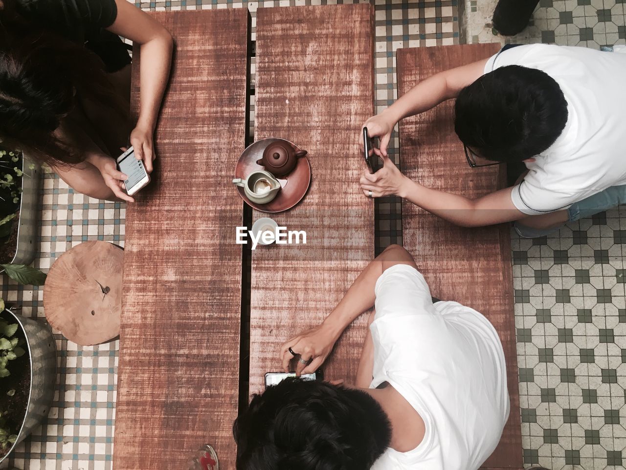 High angle view of friends using phones at table