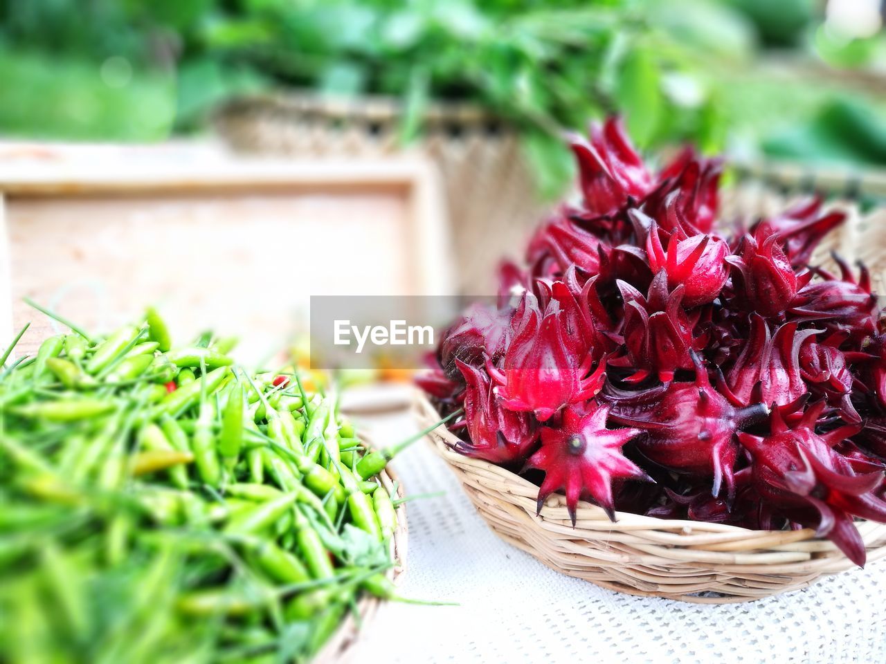 Close-up of green chili peppers and vegetable in wicker baskets on table