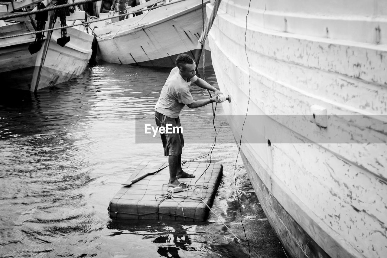 Side view of man repairing boat moored on shore