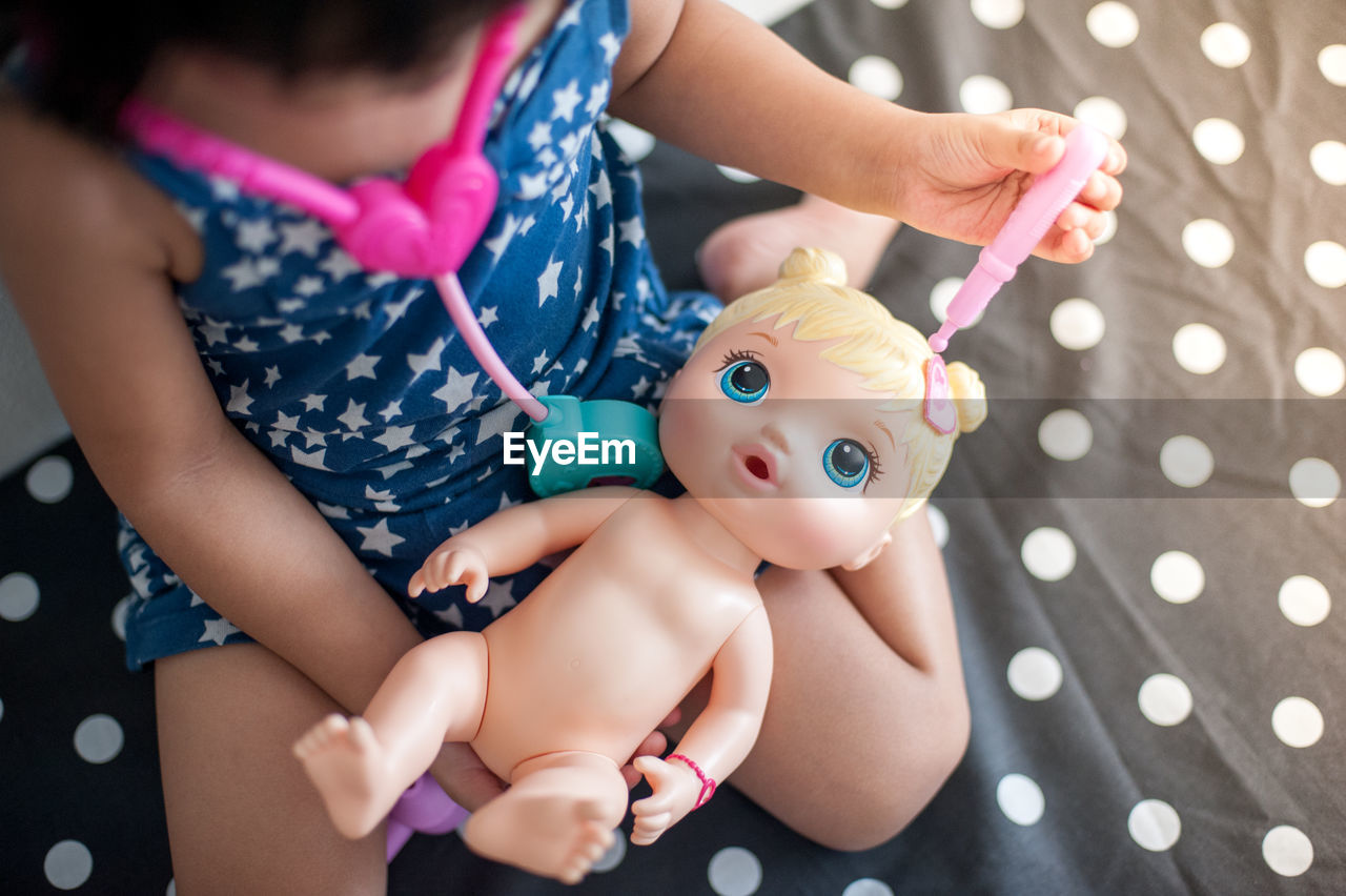 HIGH ANGLE VIEW OF BABY GIRL WITH TOY HAND