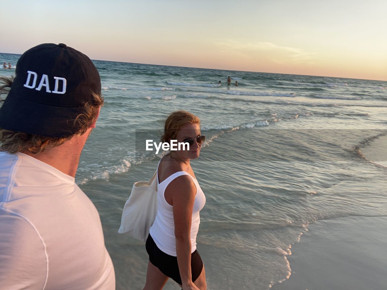 Women on beach against sky during sunset