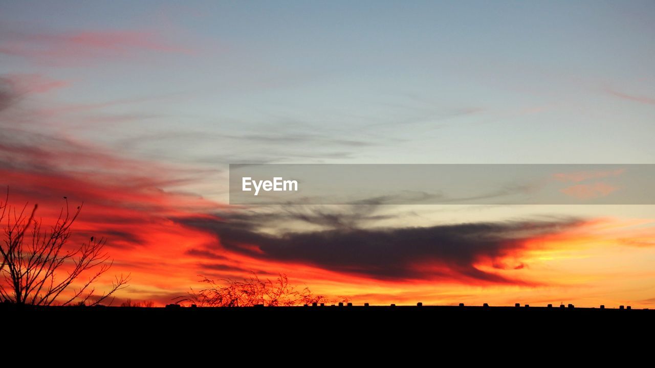 Silhouette landscape against orange sky during sunset
