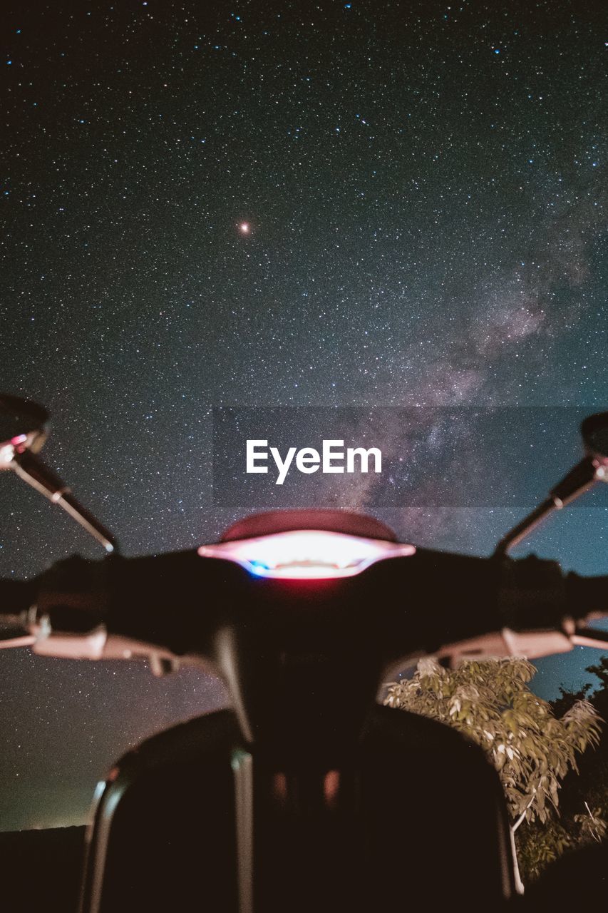 Illuminated motor scooter against sky at night