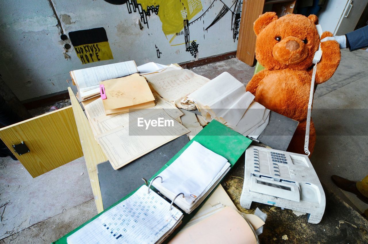 High angle view of teddy bear with documents in abandoned office