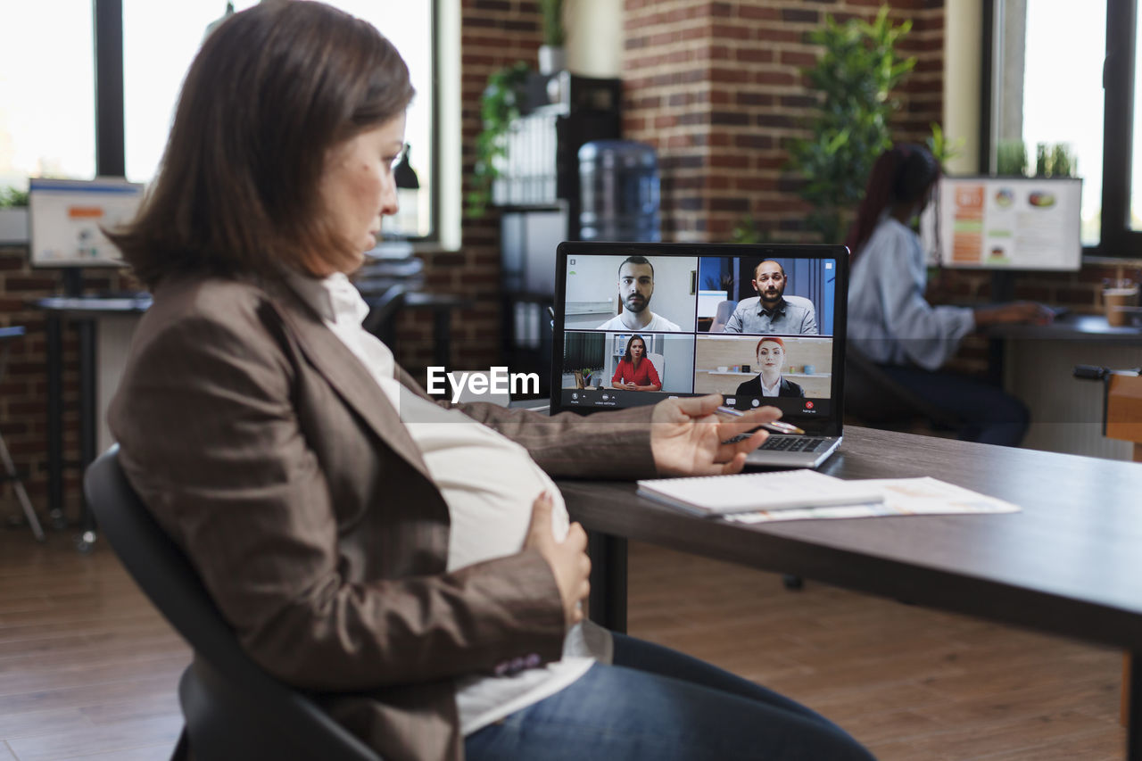 Pregnant businesswoman talking on video conference