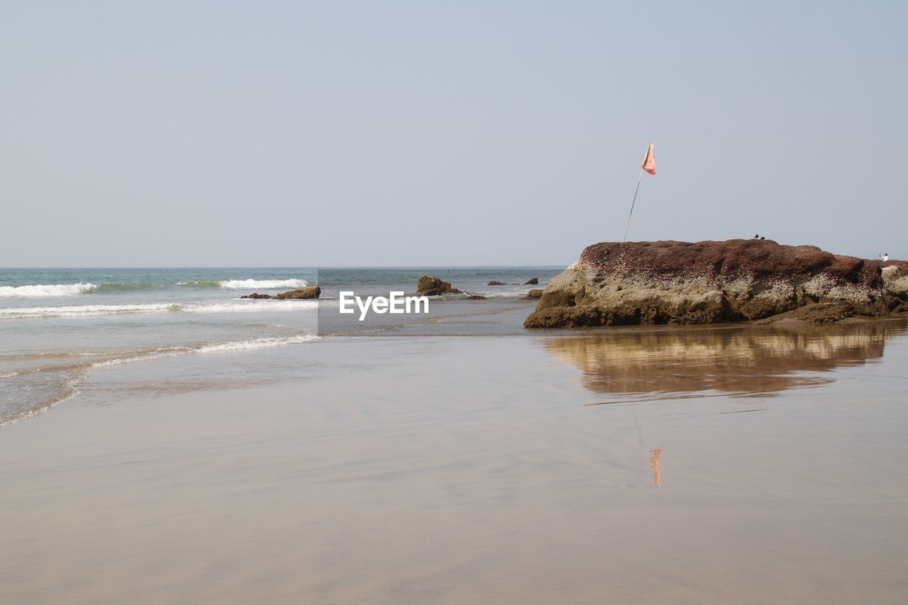 ROCKS ON BEACH AGAINST CLEAR SKY