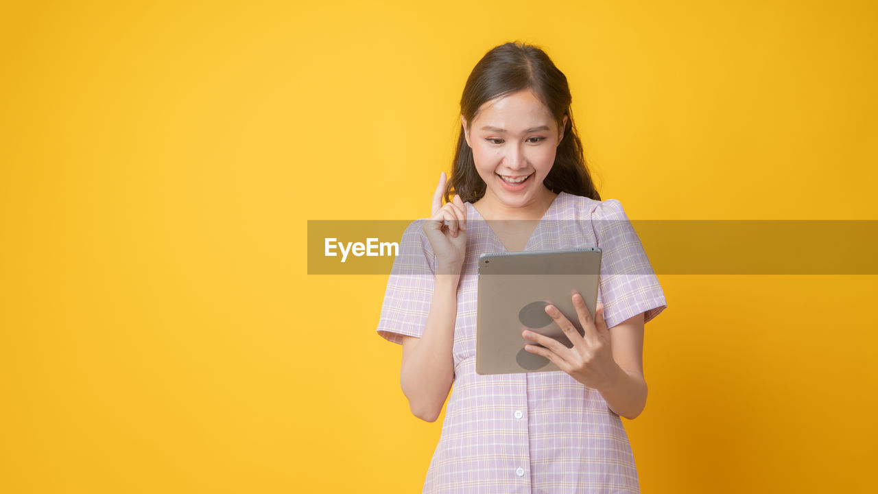 PORTRAIT OF A SMILING YOUNG WOMAN USING PHONE