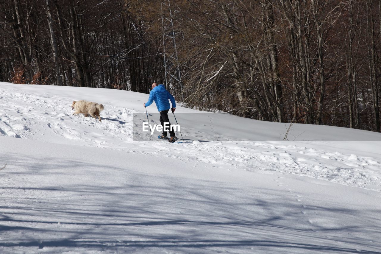 REAR VIEW OF PERSON ON SNOW COVERED LAND