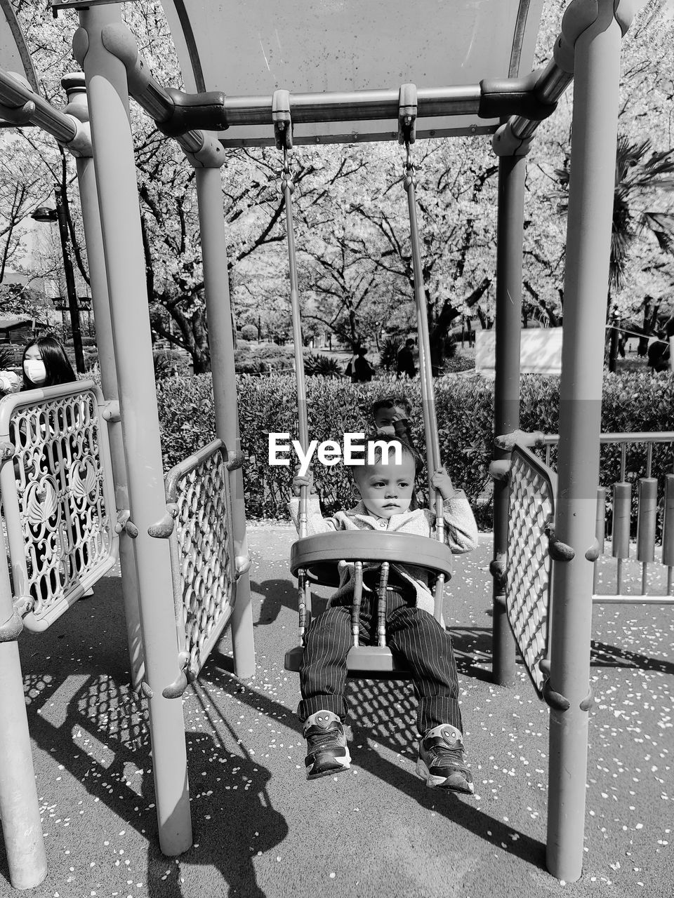 Boy sitting on swing in park