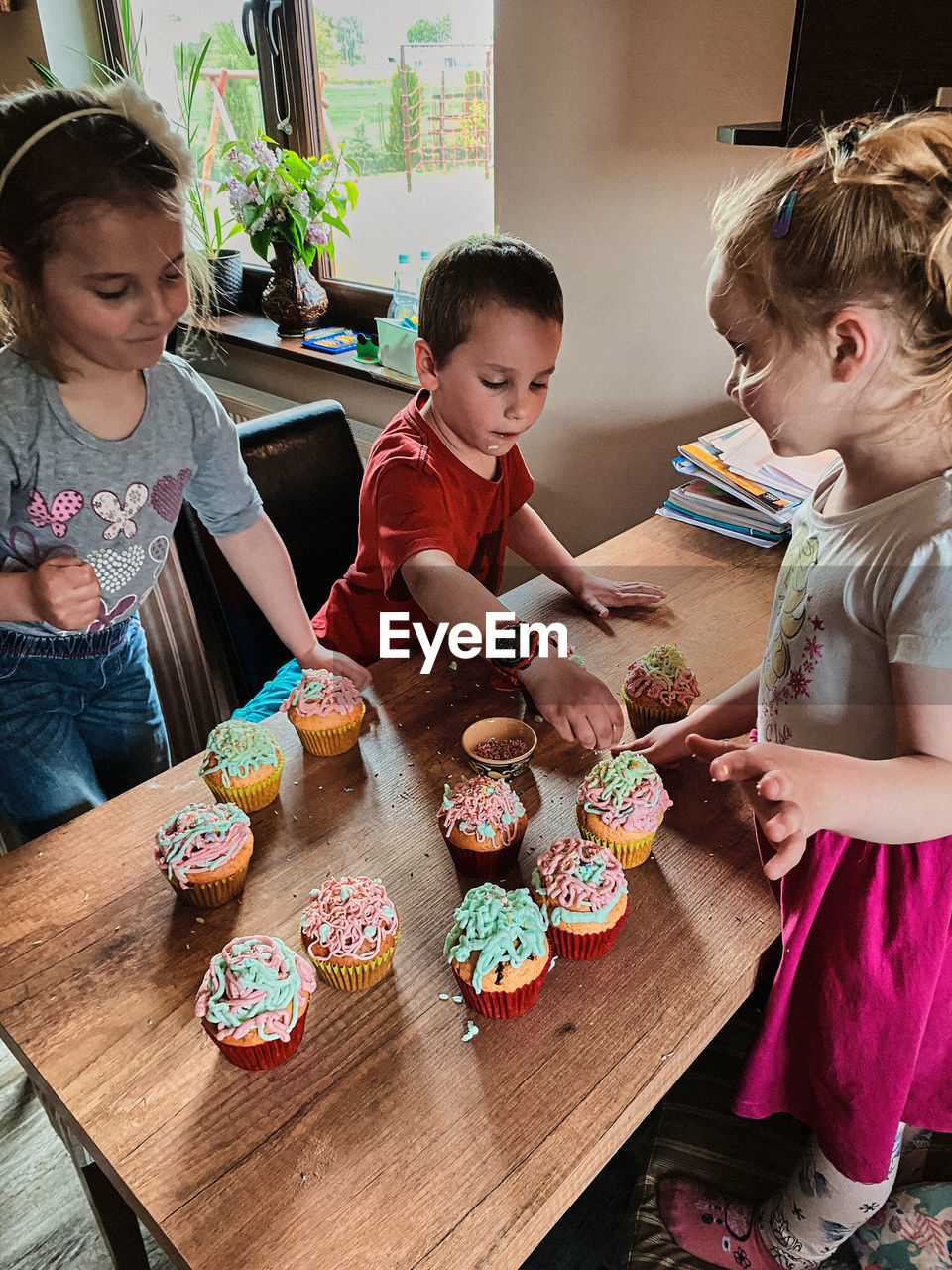 Group of children baking cupcakes, preparing ingredients, topping, sprinkles for decorating cookies