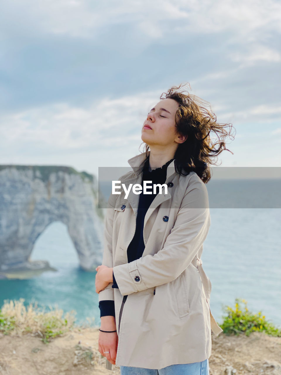 Young woman looking at sea shore against sky