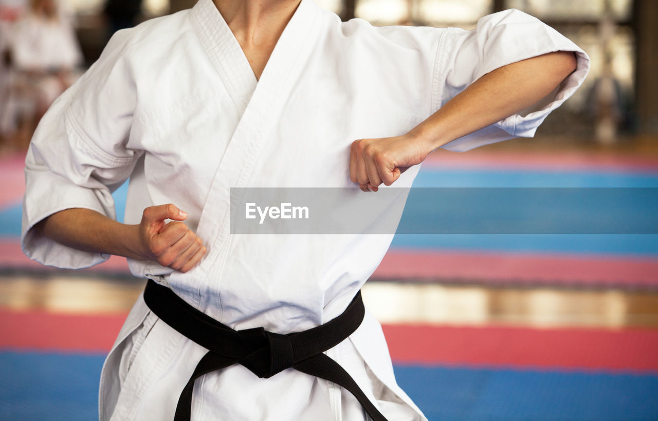 Midsection of man practicing karate on carpet