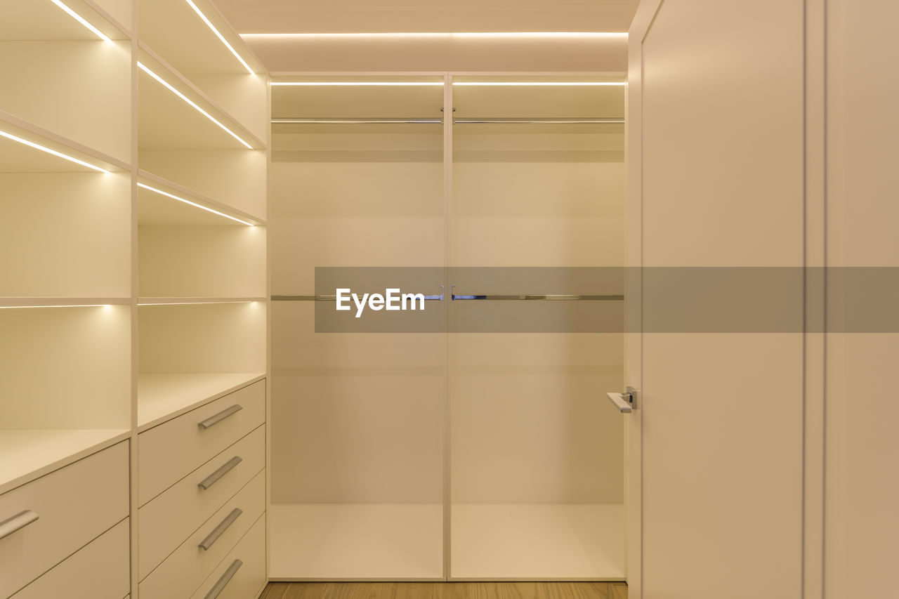 Spacious, empty, modern backlit wardrobe in light colours