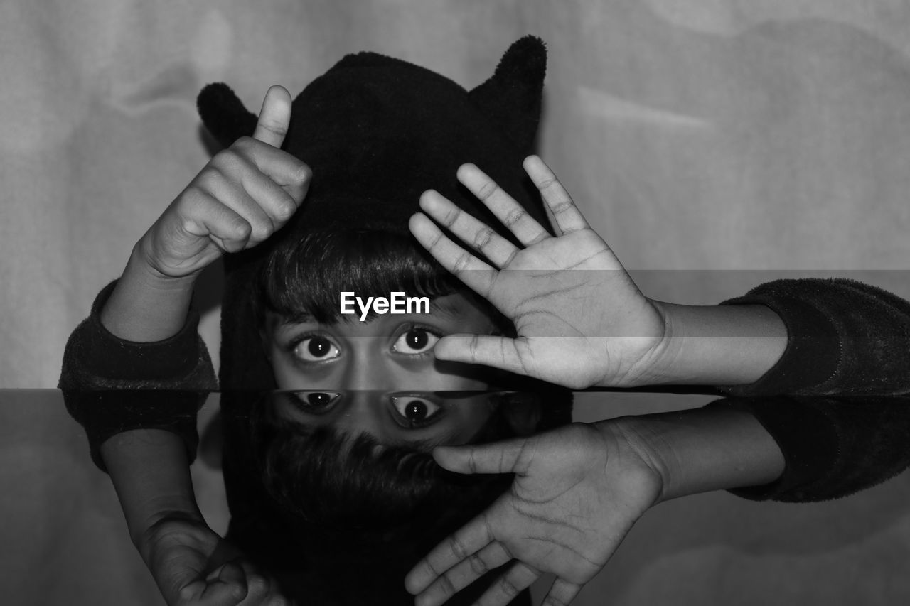 Portrait of boy gesturing while hiding behind table