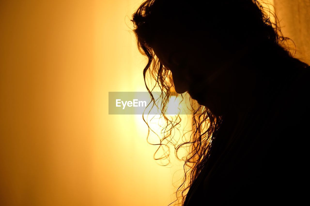 Close-up of silhouette woman sitting at home