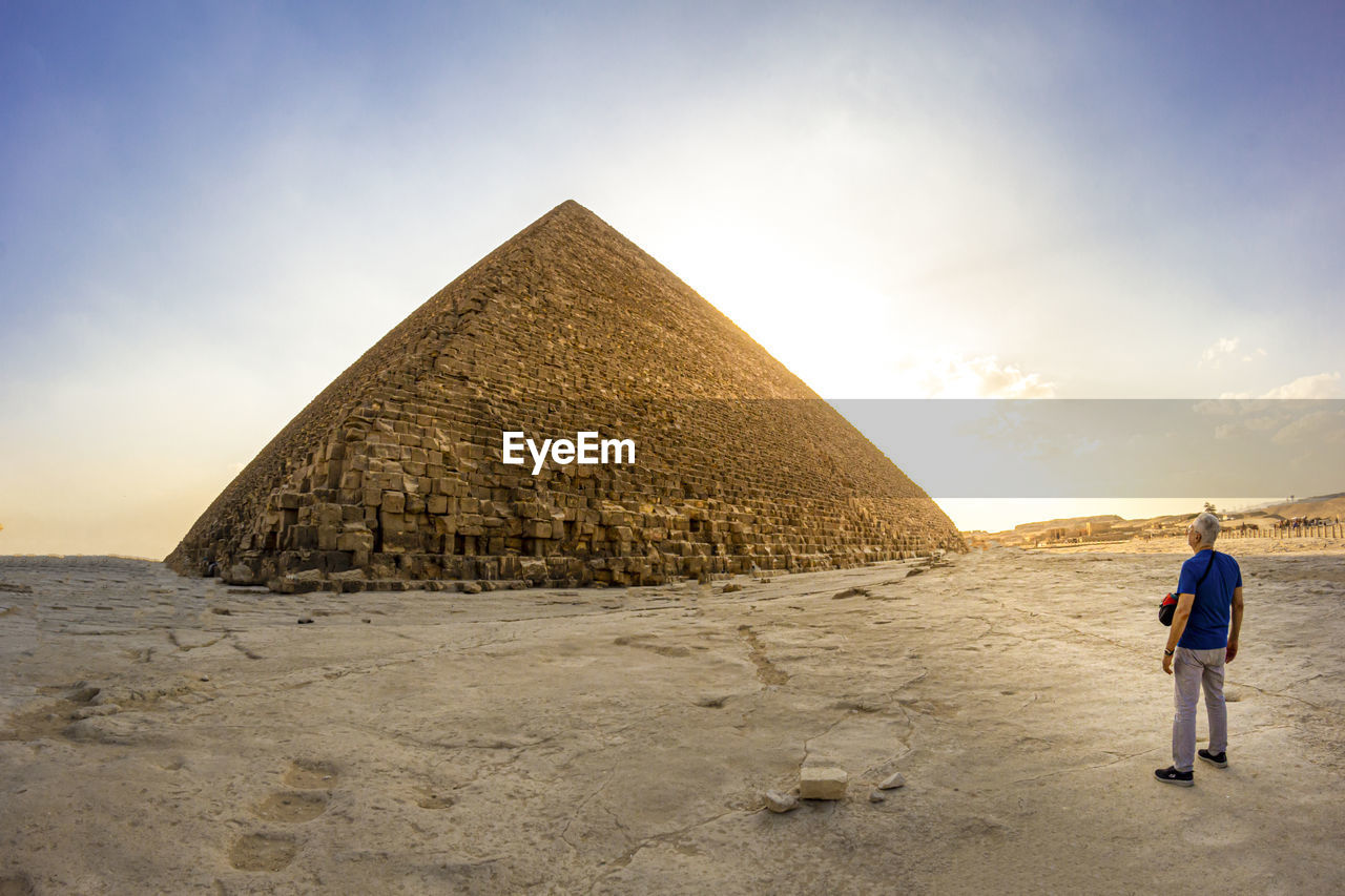 Rear view of senior man standing against pyramid against sky