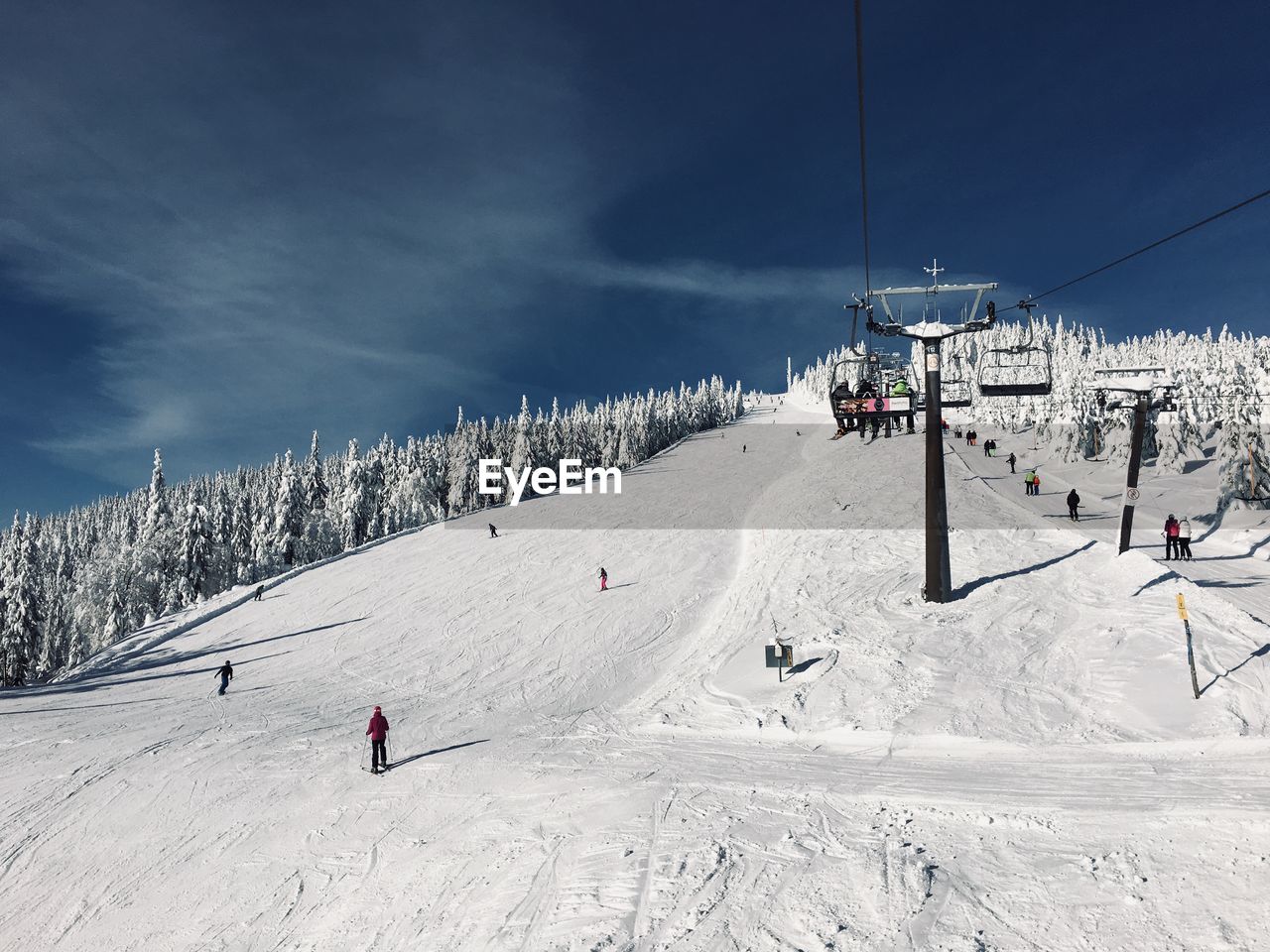 Ski lift by snow covered mountain against sky