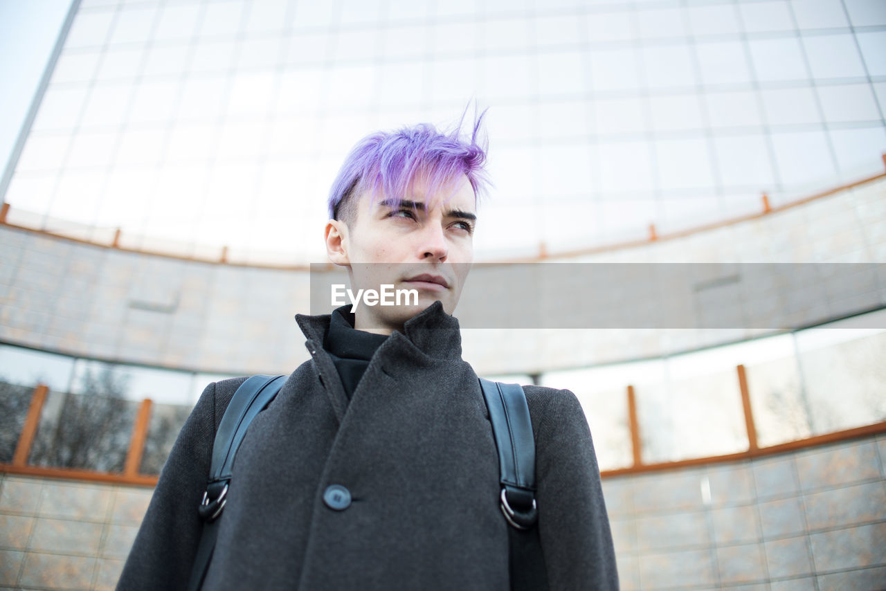 Low angle view of homosexual man looking away while standing outdoors