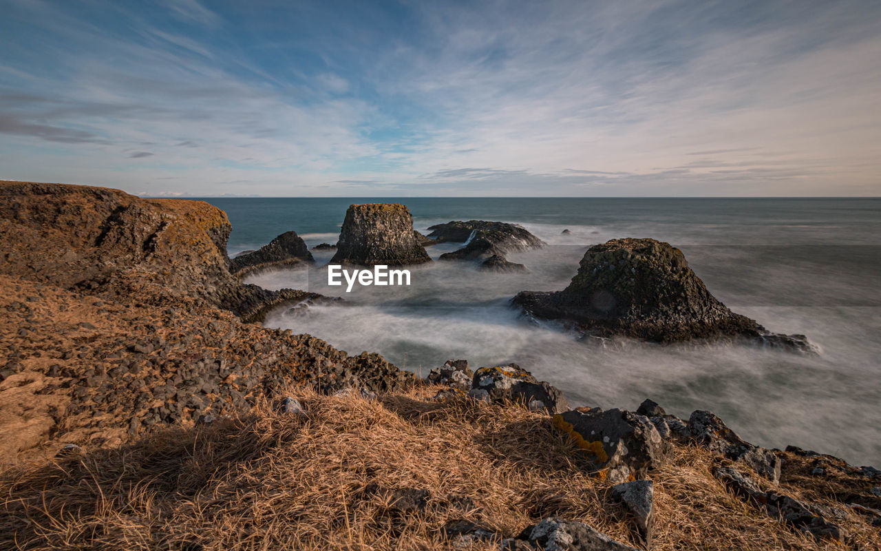 Full frame view of panoramic coastal seascape with volcanic rock before sunset