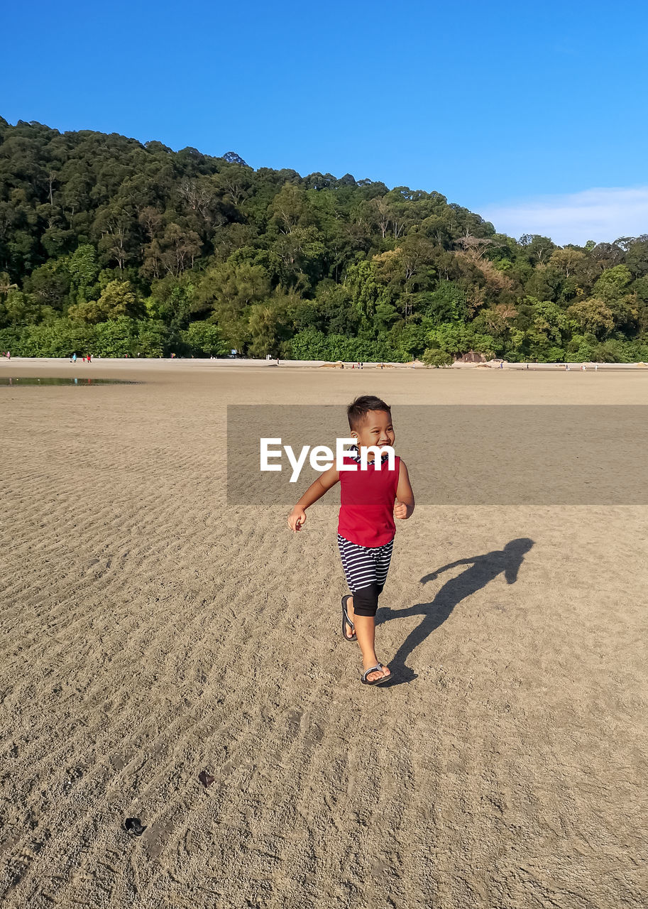 Full length of boy standing on land against sky