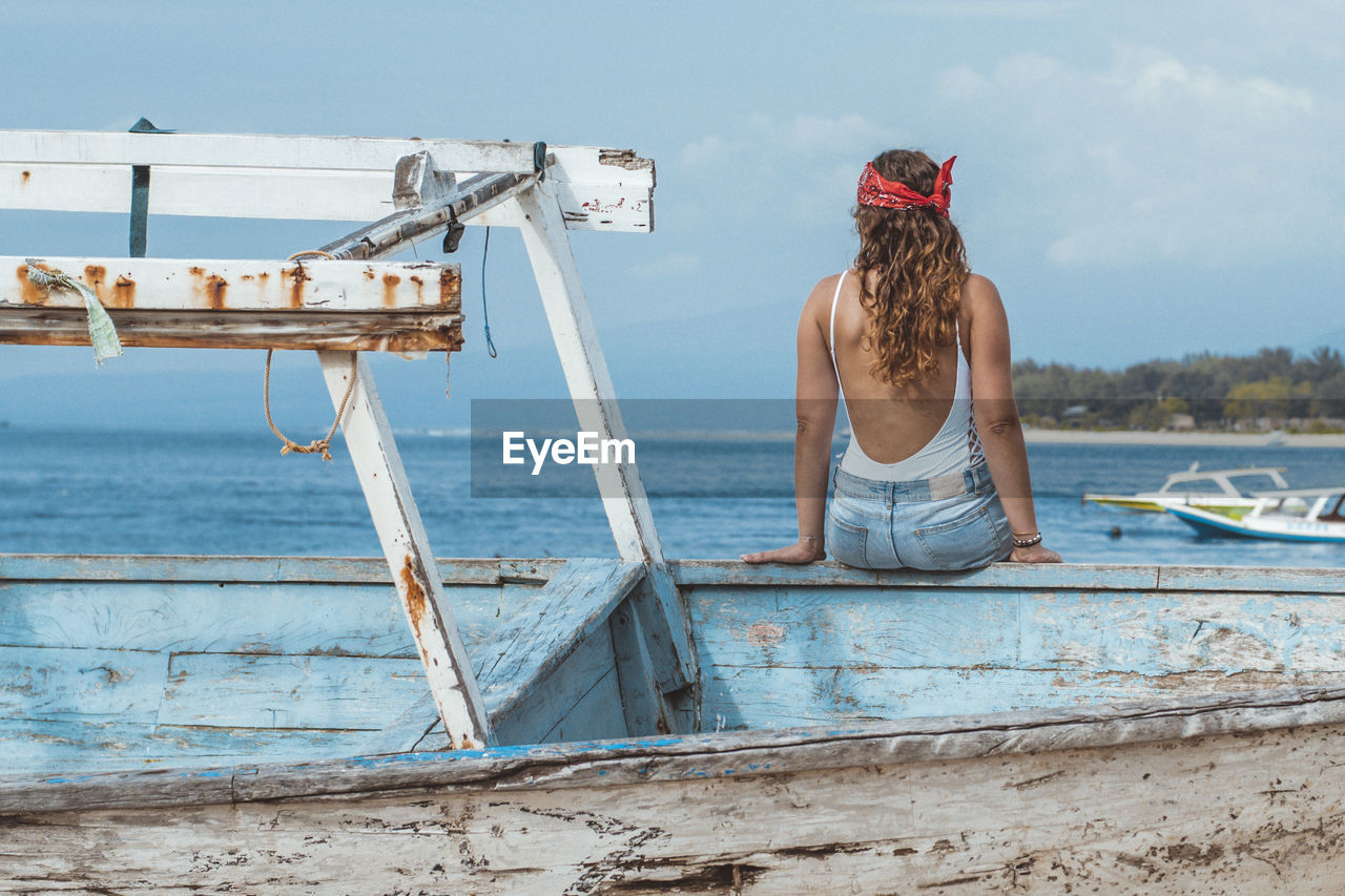 Rear view of woman on beach against sky