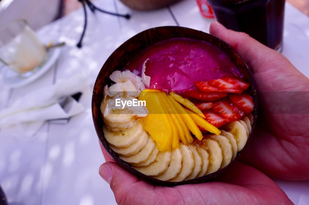 Close-up of hand holding fruits in bowl