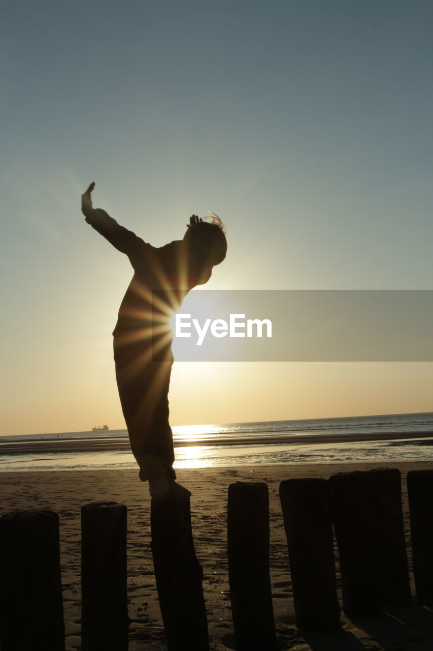 Silhouette man standing at beach during sunset