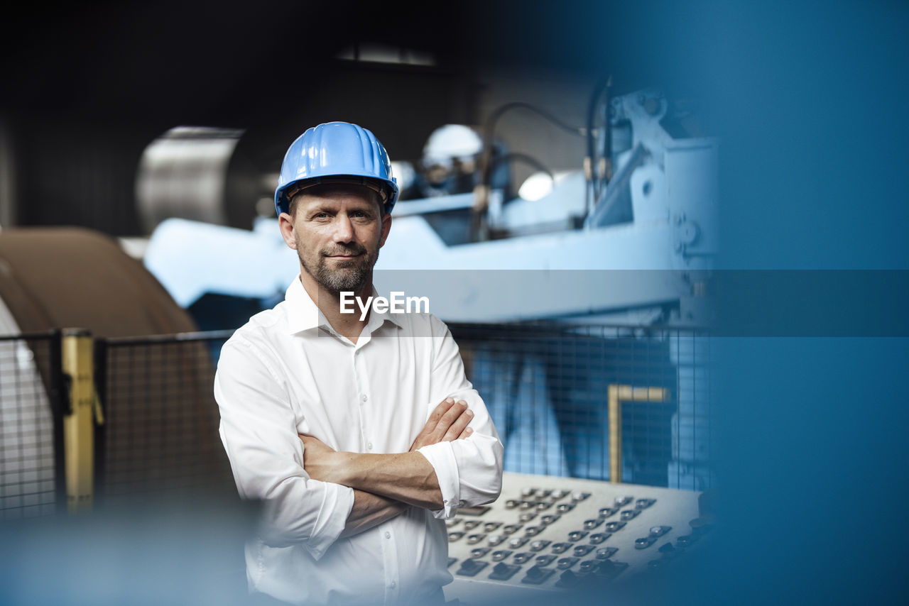 Businessman smiling with arms crossed at factory