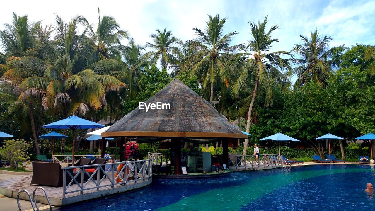 Gazebo by swimming pool against sky