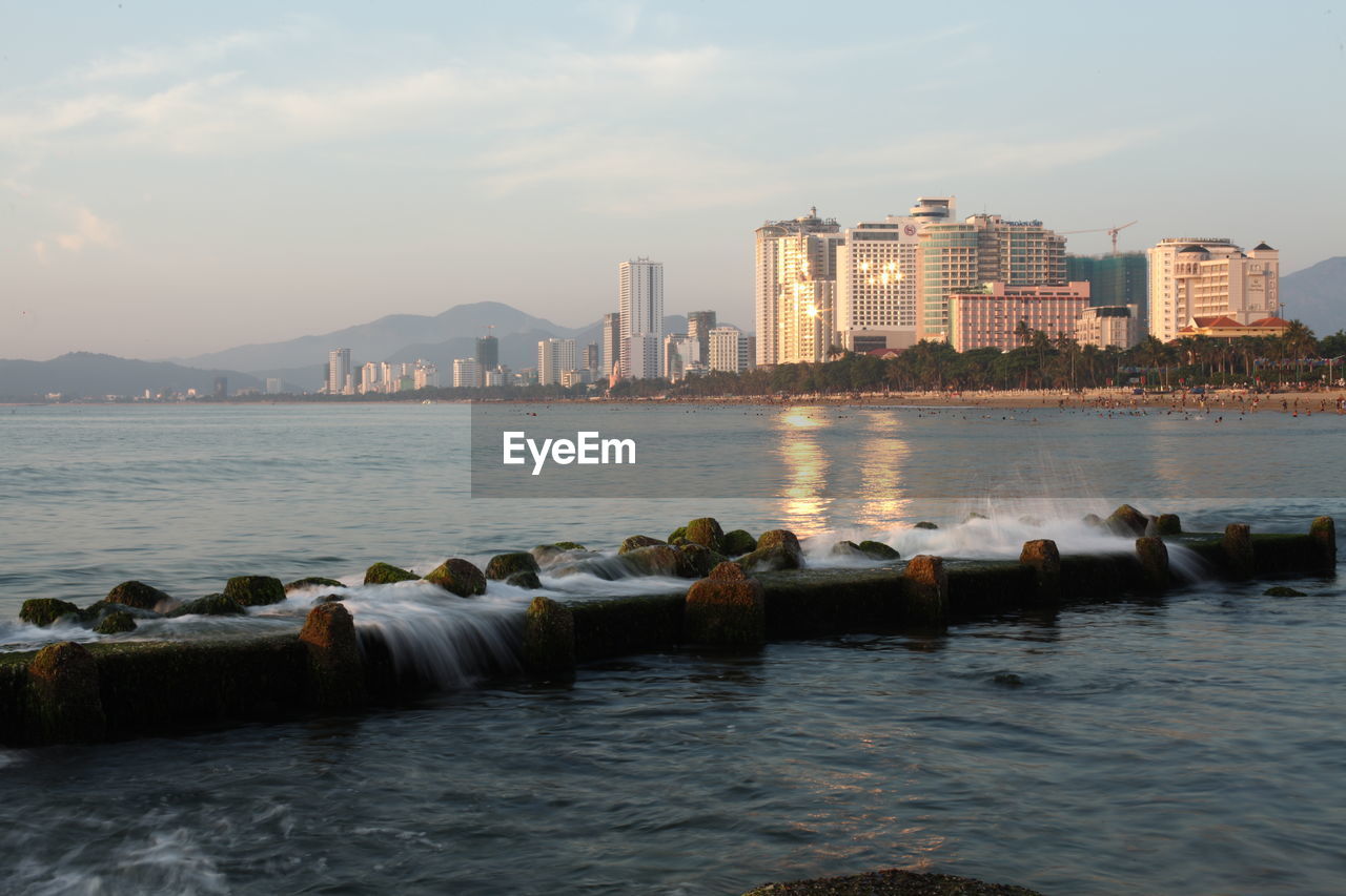 Sea by buildings against sky in city