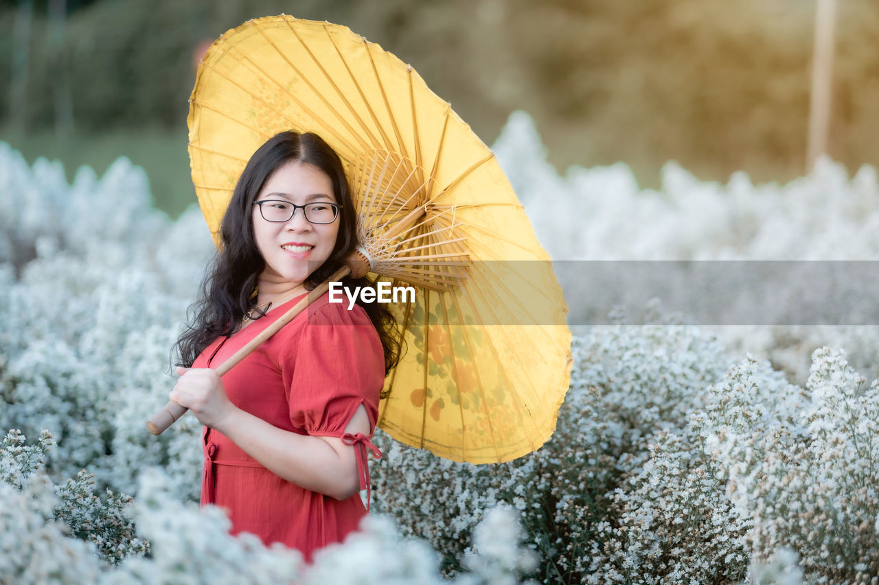 PORTRAIT OF SMILING WOMAN STANDING OUTDOORS