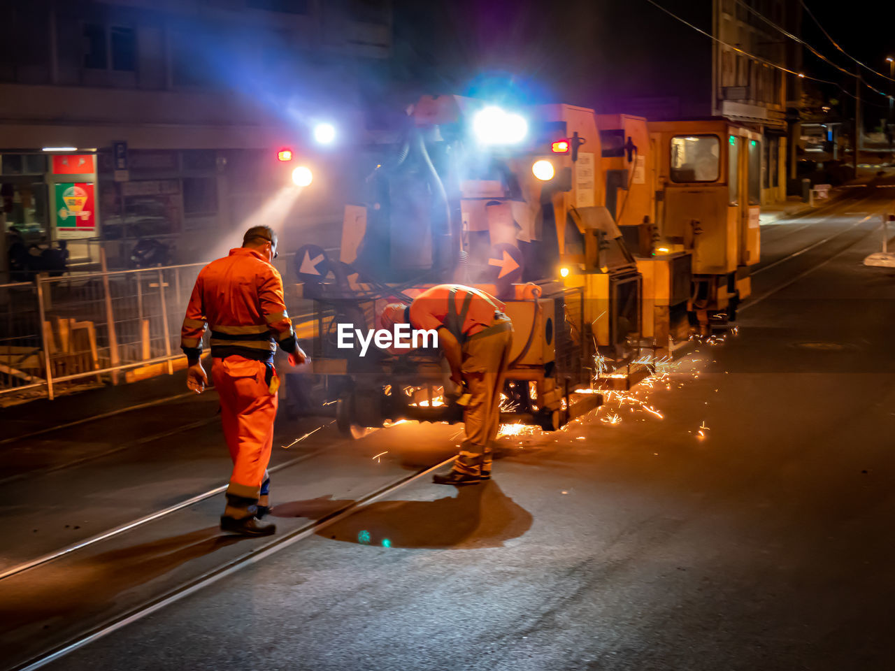 Rear view of people standing on road at night