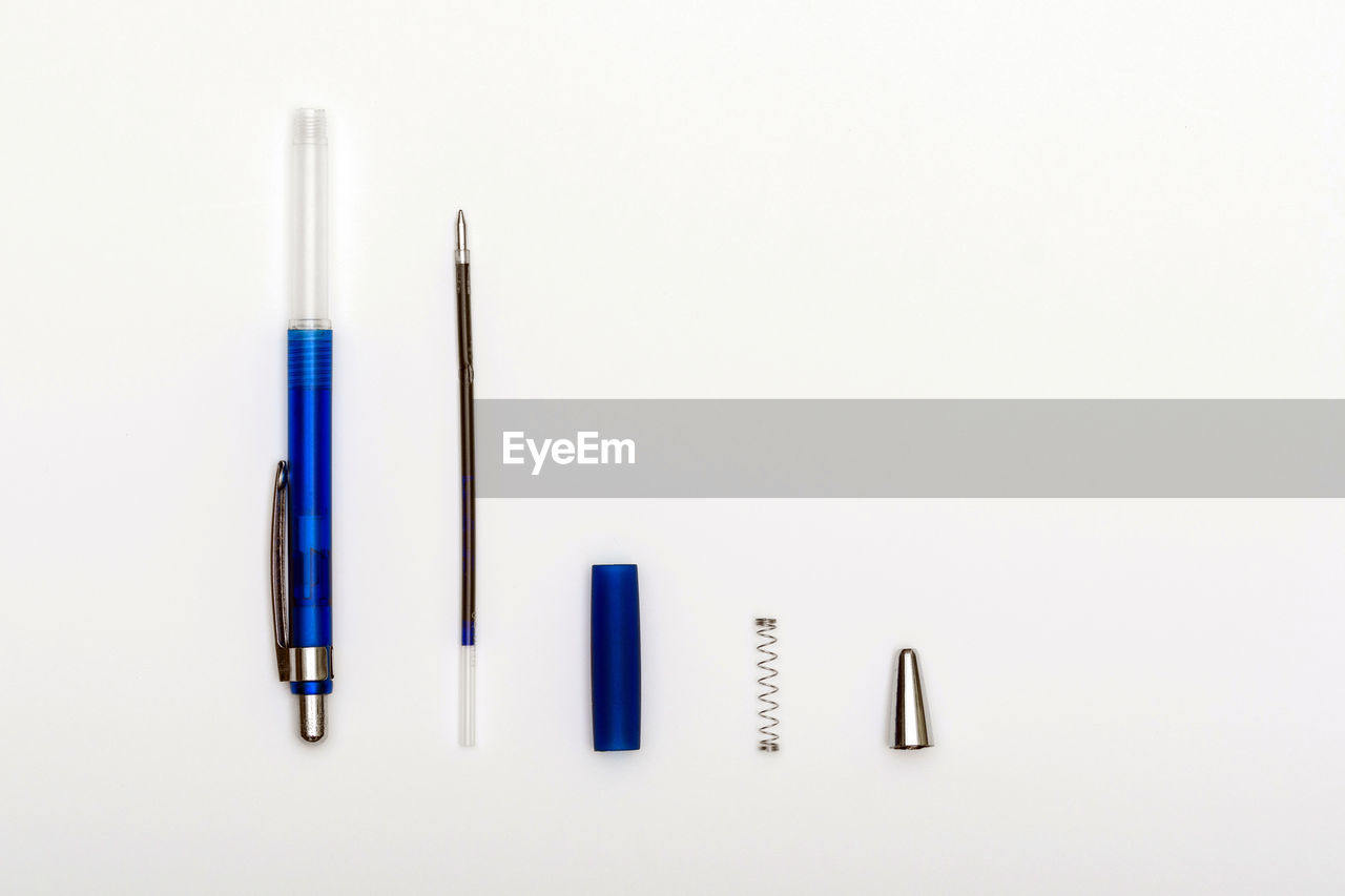Directly above shot of pen with parts on white background