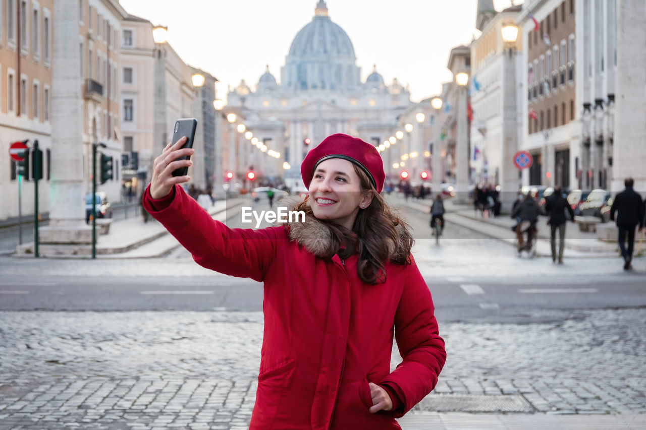 Portrait of smiling woman standing in city during winter