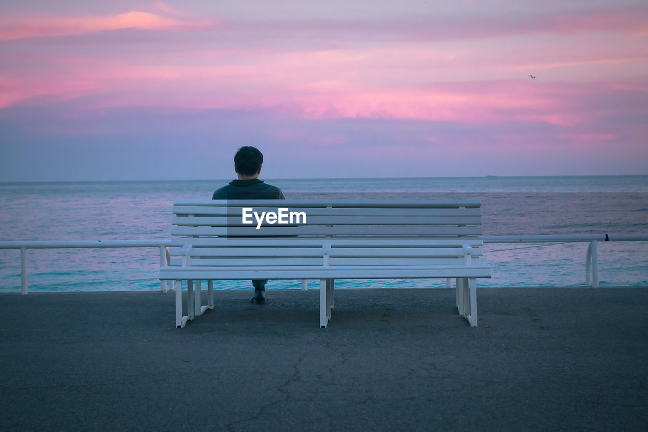 Rear view of a man overlooking calm sea